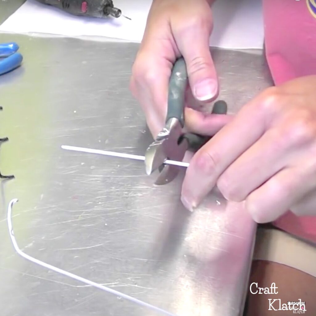 Two hands cutting wire hanger with pliers this is another opportunity to work in a recycled material