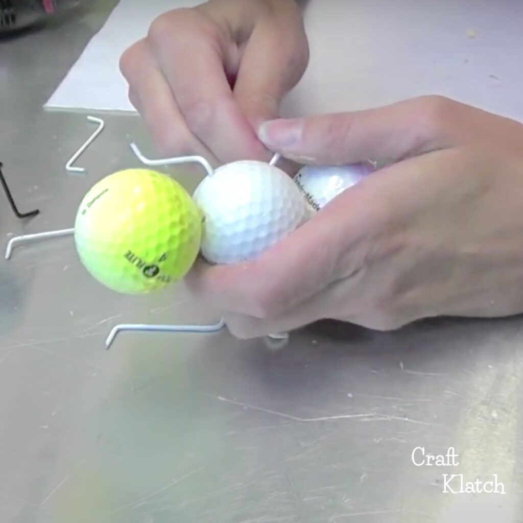 Inserting wire hanger legs into golf balls for giant garden ants