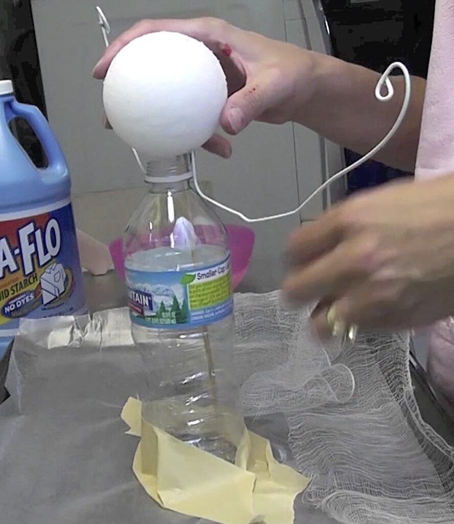 Create an armature with a styrofoam ball, water bottle and wire hanger