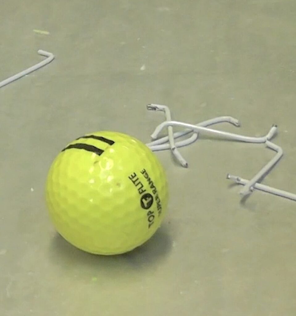 Golf balls with pieces or wire hangers bent into the S shape