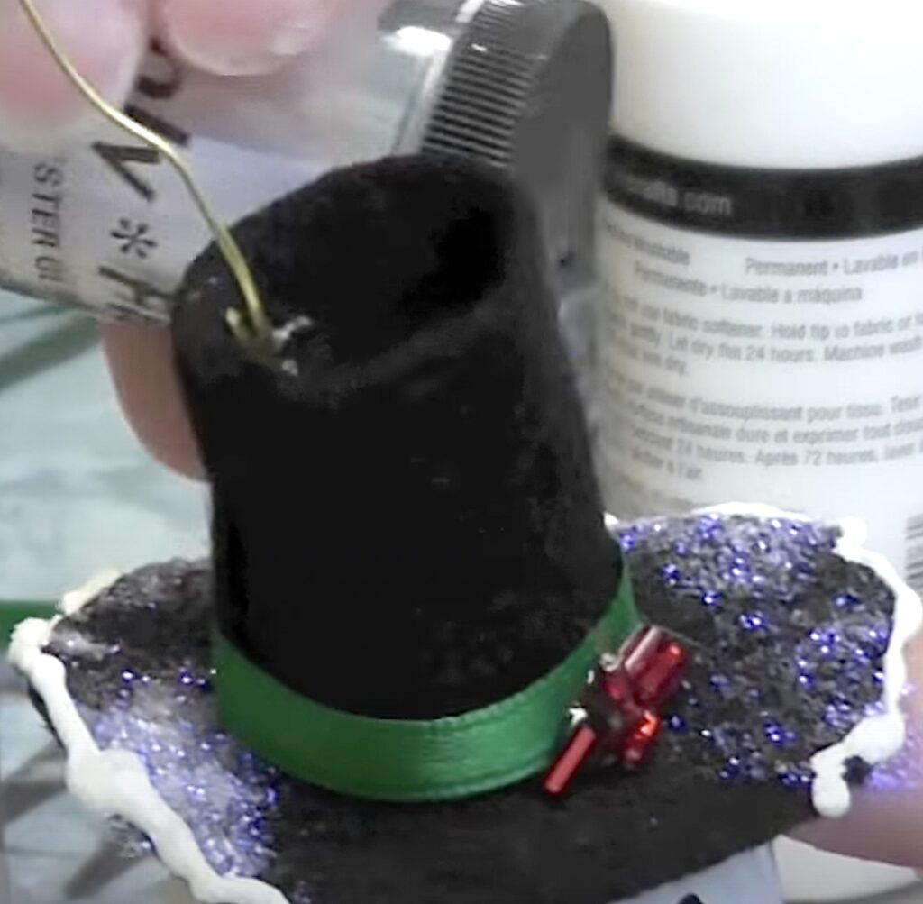 Add white paint to edge of hat and sprinkle with white glitter for icy snow effect