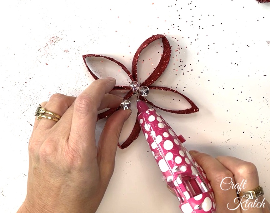 Gluing clear marbles into center of red toilet paper flower Christmas craft