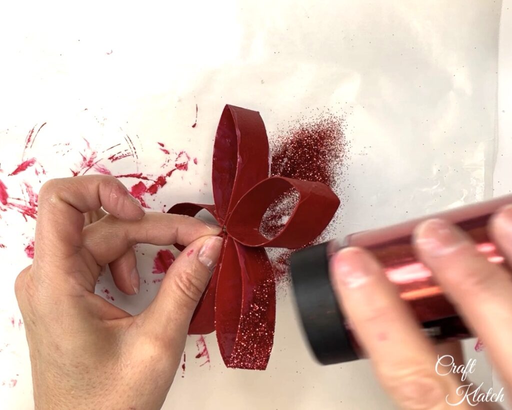 Sprinkling red glitter on toilet paper roll flower craft