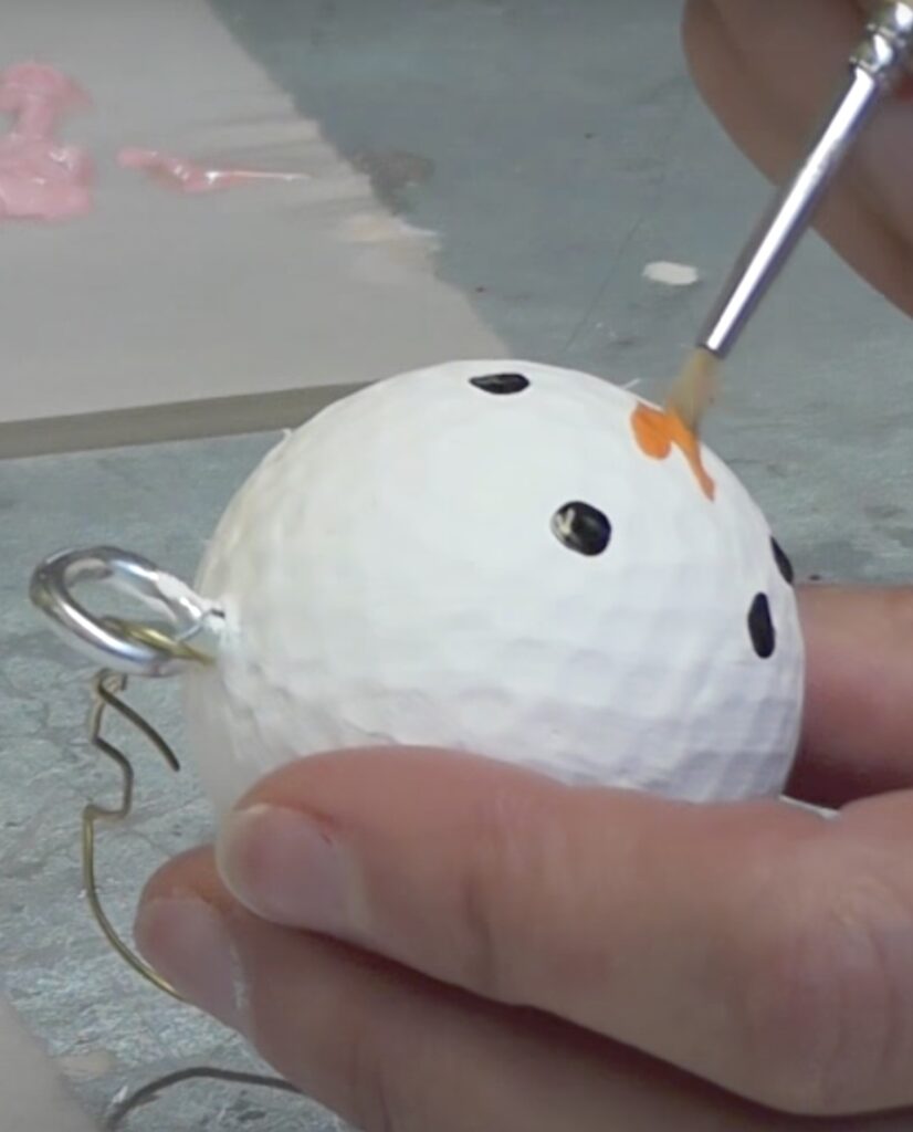 Paint orange carrot nose onto the white golf ball snowman
