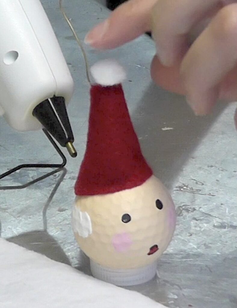Glue on hat and pom pom to the fun golf ball Santa