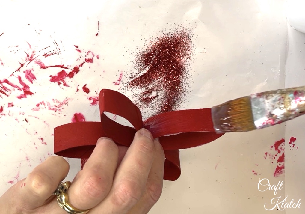 Brushing glue onto red toilet paper roll craft flower