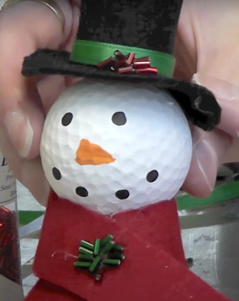 Add red and green bugle beads to the snowman's hat and scarf