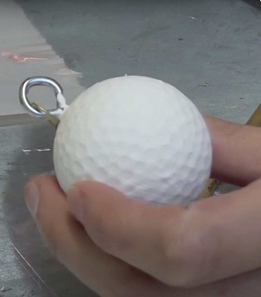 Golf ball painted white with an eye screw inserted