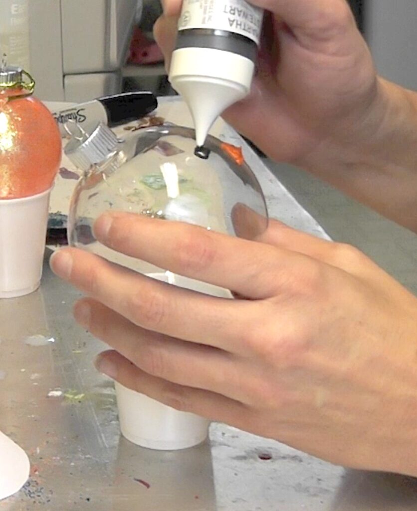 Paint snowman face onto glass ornament