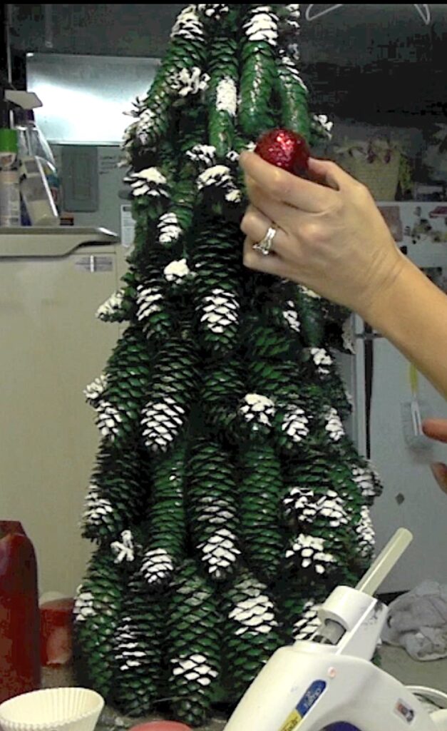 Glue red glitter covered golf balls onto the Christmas tree as ornaments