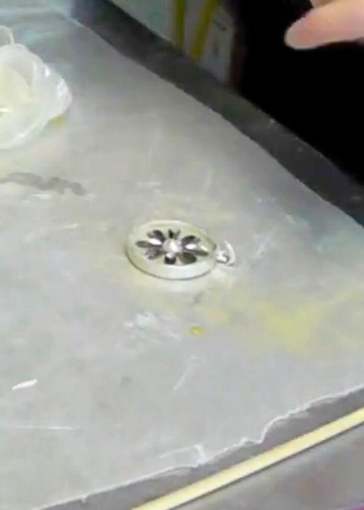 Pressed the metal flower into the epoxy clay into a bezel while showing how to make metal jewelry