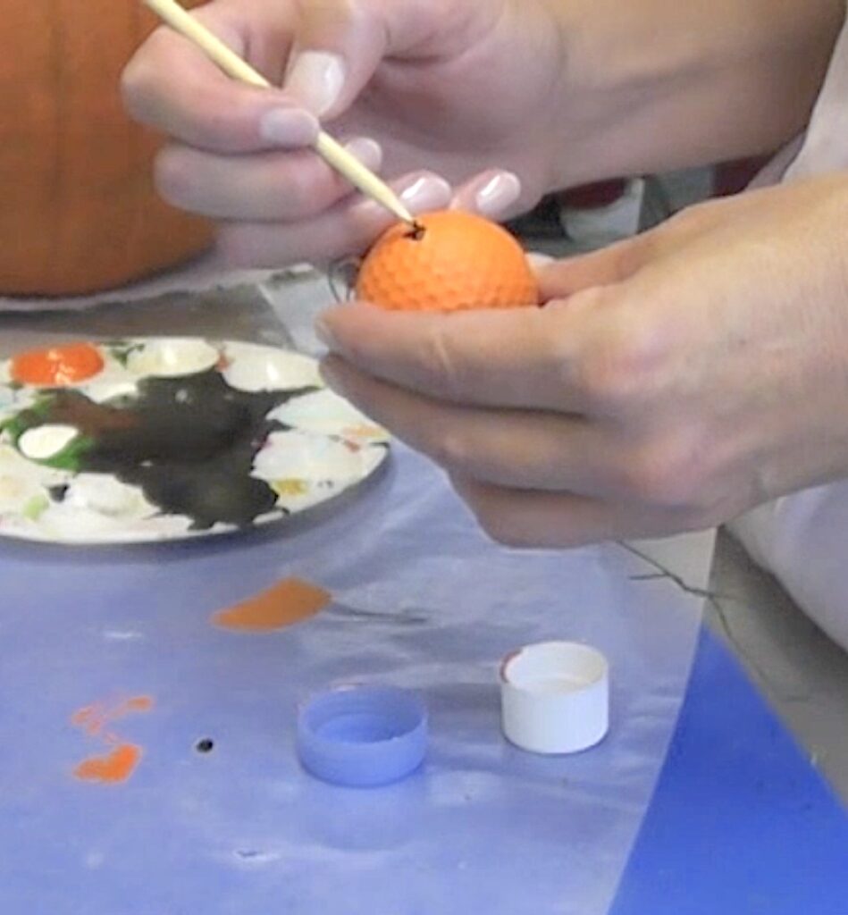 Paint on fun pumpkin face with skewer stick and black paint