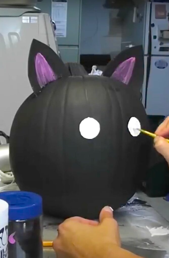 Painting the white eyes on the black cat pumkin painted for Halloween