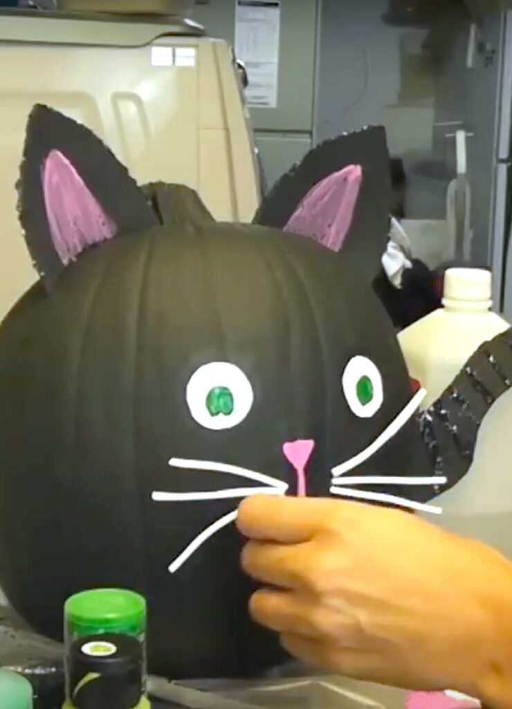 Gluing white whiskers on Black cat pumpkin