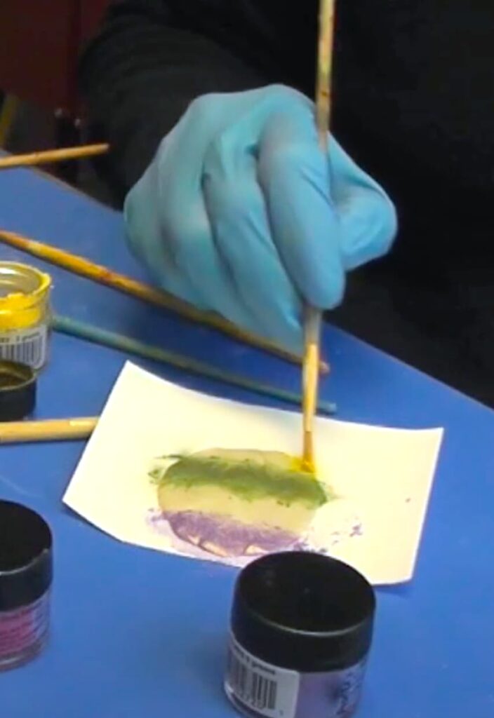 Brushing pigment powder onto the epoxy clay which will be the back of the clay jewelry