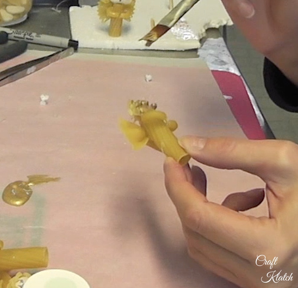 Painting pasta angel craft with gold paint