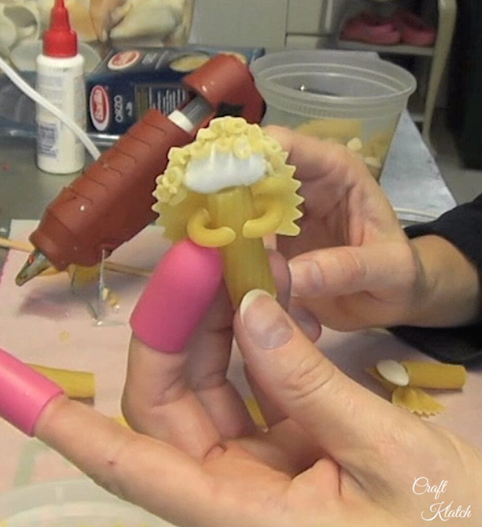 Putting together the Christmas angel noodle crafts by giving the pasta angel hair