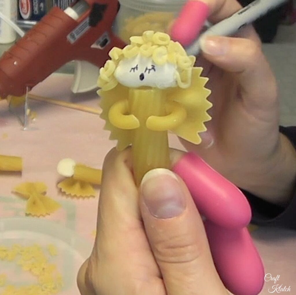 With permanent marker, draw a face on the pasta Christmas angel