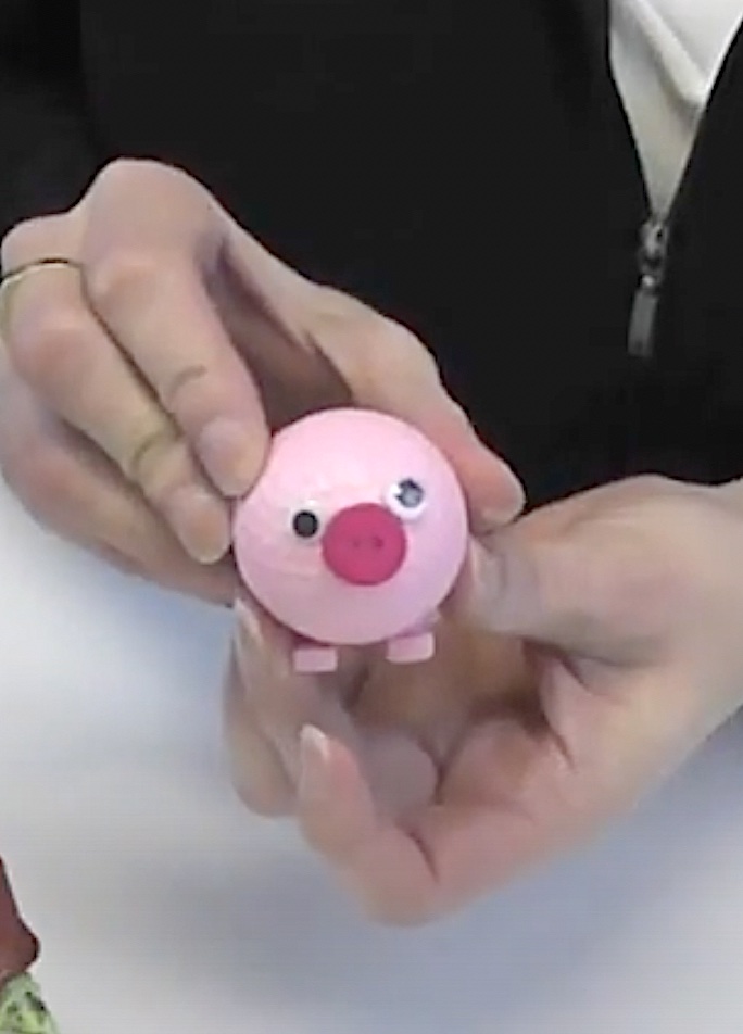 Pink golf ball pig with ears, button nose and google eyes
