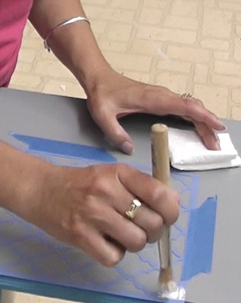 stenciling on wood table top with white paint and trellis stencil