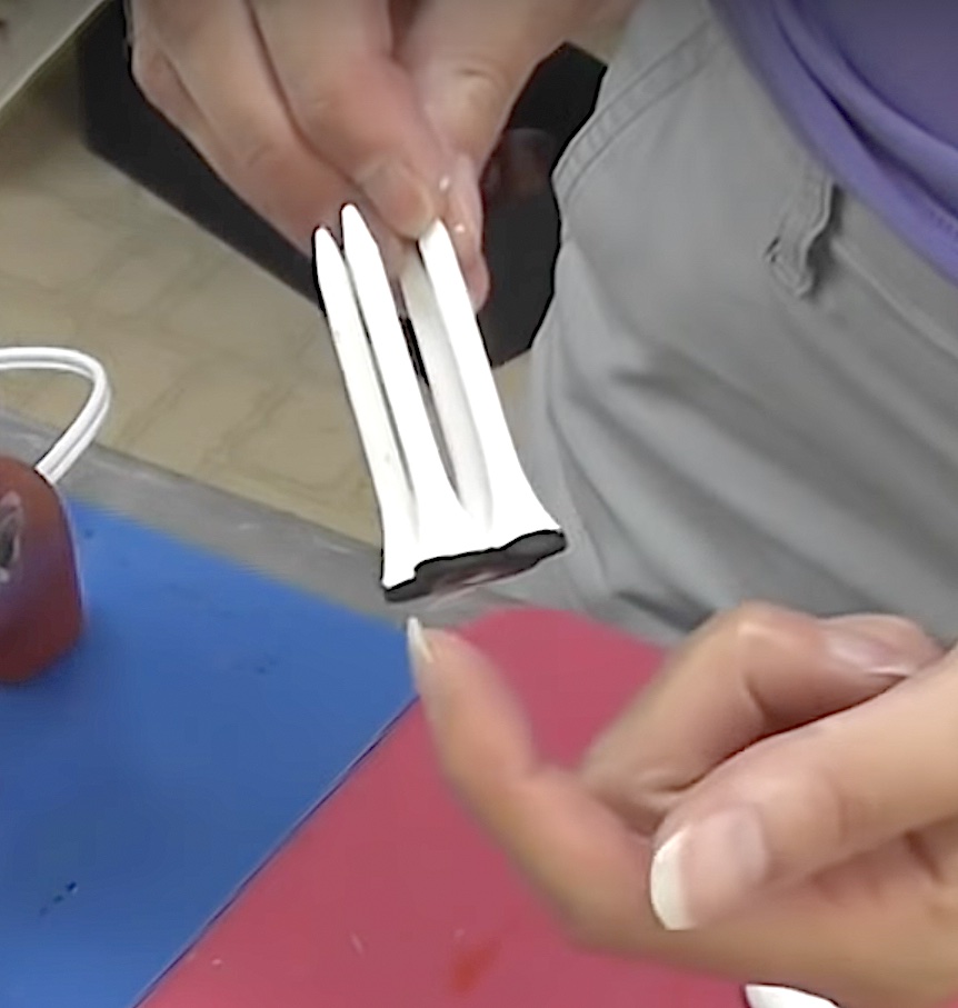 Four golf tees painted white and black stripe at bottom