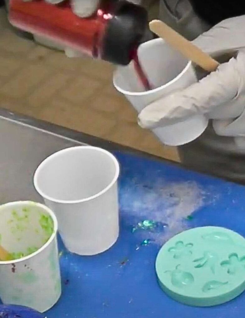 Pouring resin glitter into resin for the crab ring