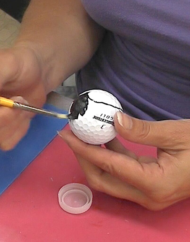 Paint the area outside of the heart drawn on the golf ball black