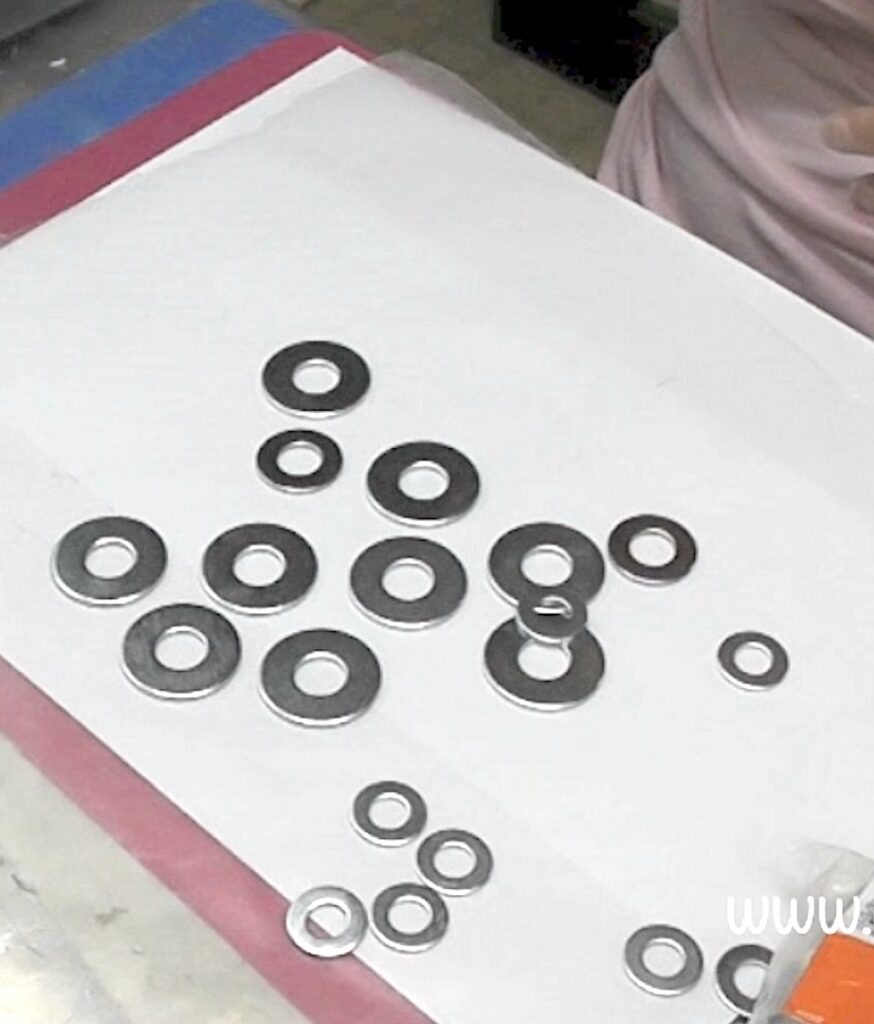 Silver washers laid out on white paper for jewelry making