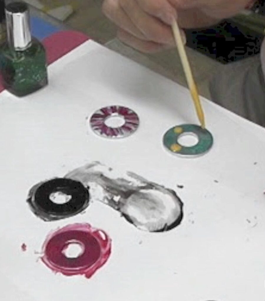 Dripping yellow nail polish onto green polish for washer necklaces