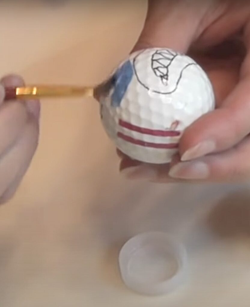 paint golf ball blue around drawn face