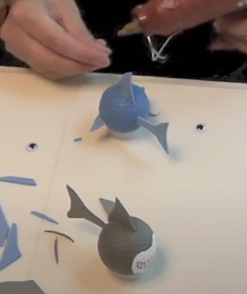 Glue on shark fins and tails cut out of blue and gray craft foam