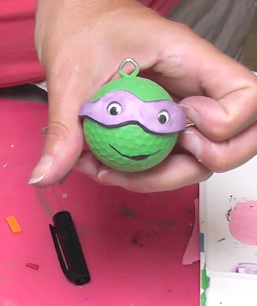 Holding teenage mutant ninja turtles keychain with purple mask