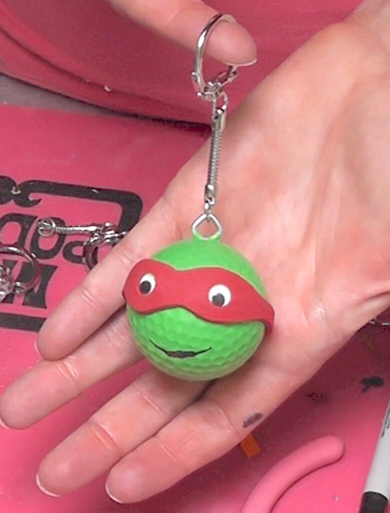 holding teenage mutant ninja turtles keychains with red mask