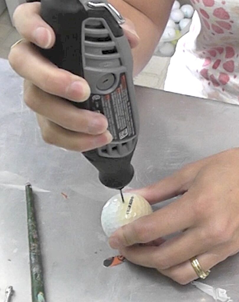 Get started on the bat decoration for Halloween by drilling a hole into golf ball