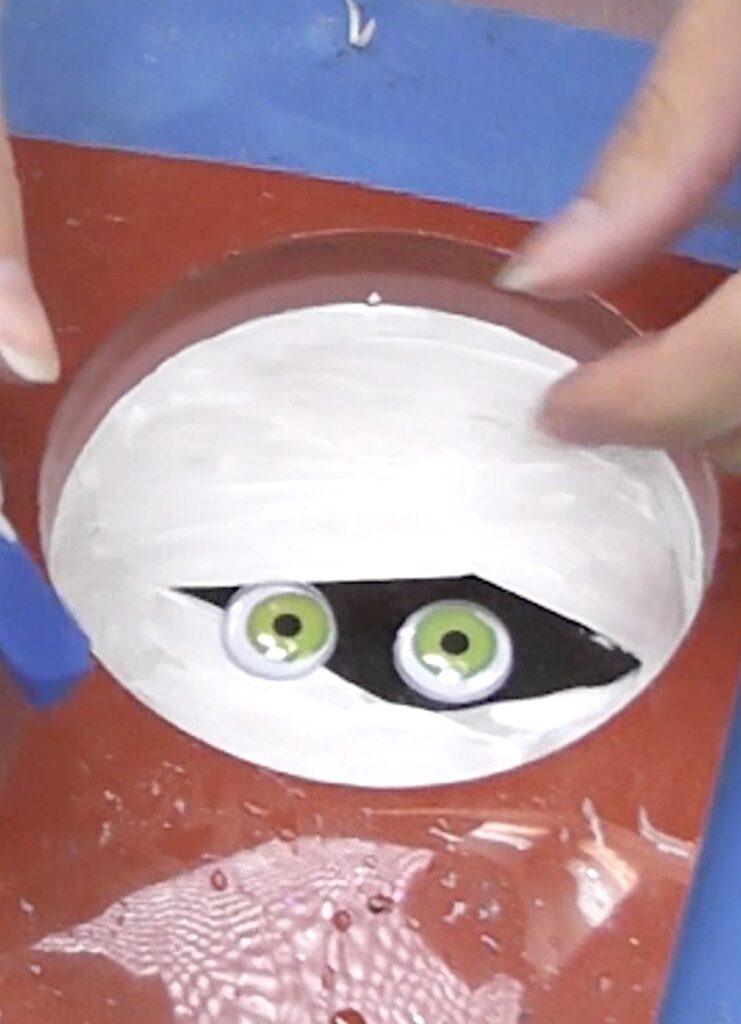 Glue the wiggle eyes on the mummy coaster