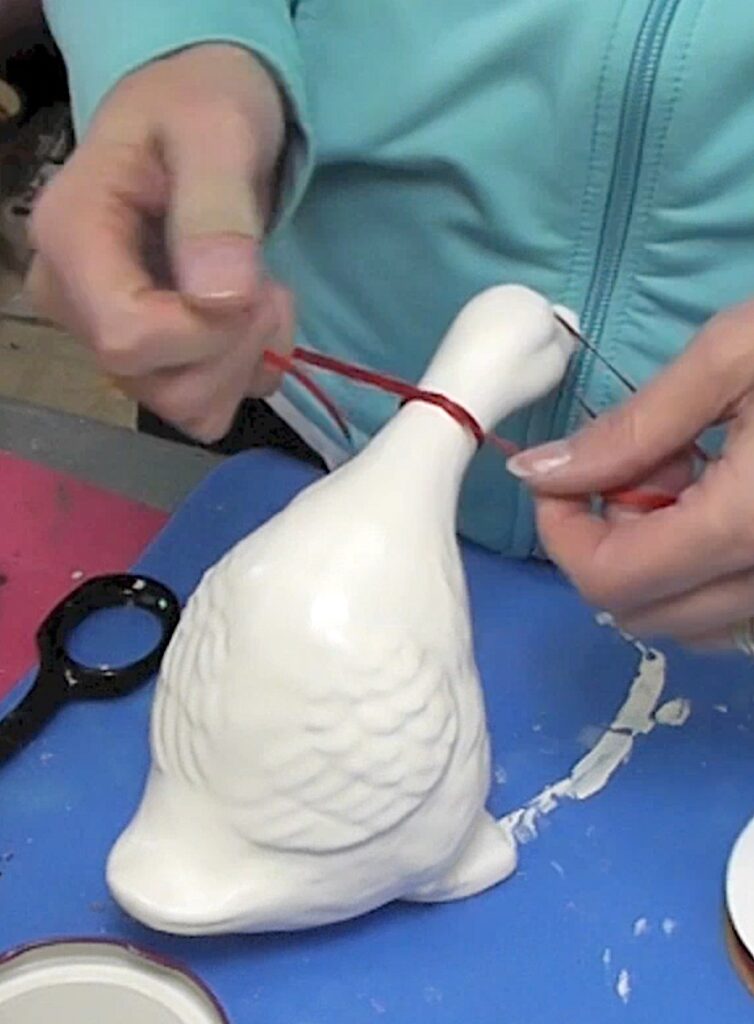 Tie a thin red ribbon around the duck