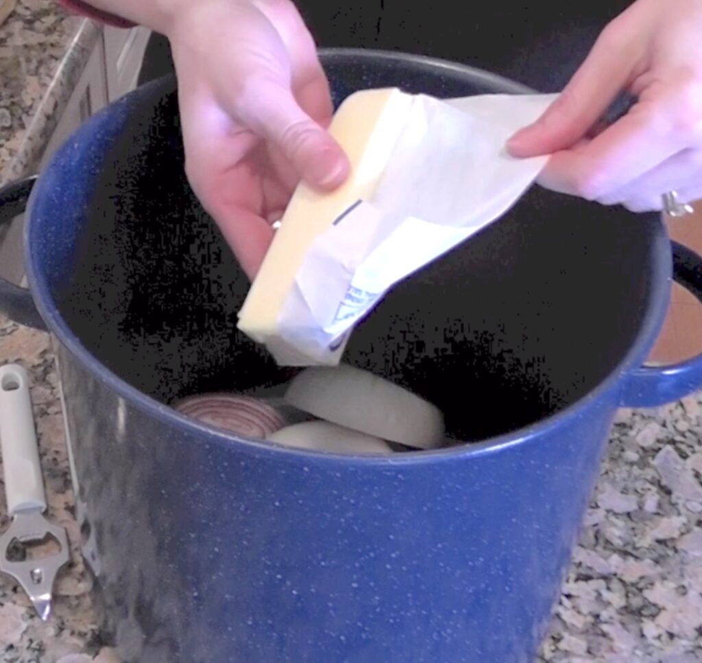 Unwrapping butter and putting it in pot with sliced onions for the beer brats