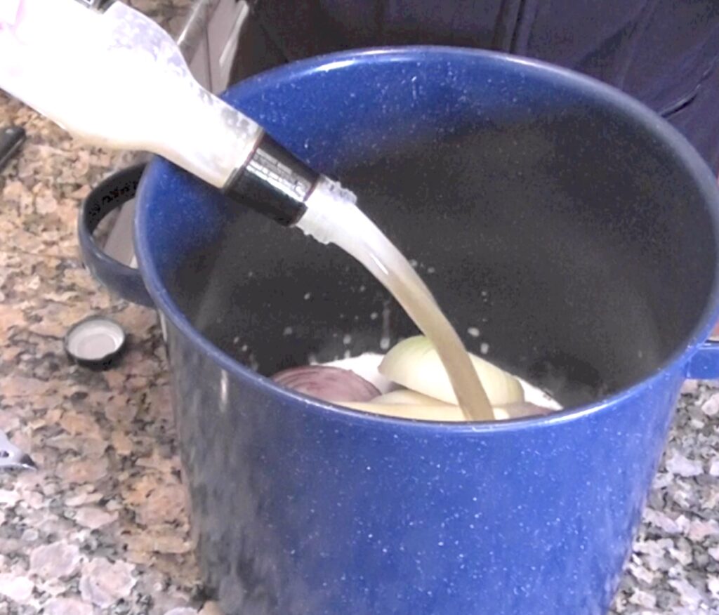 Add bottle of beer to onions and butter in cooking pot for beer brats