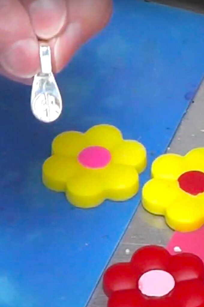Holding silver bezel with spring flower pendants in the background