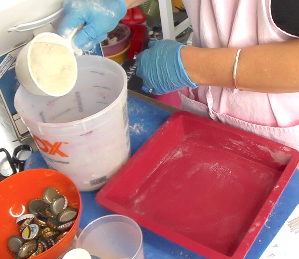 Add powdered concrete to bucket of water with silicone mold and beer bottle caps ready