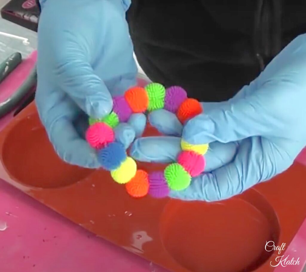 Holding colorful koosh ball bracelet for the splash of color resin diy