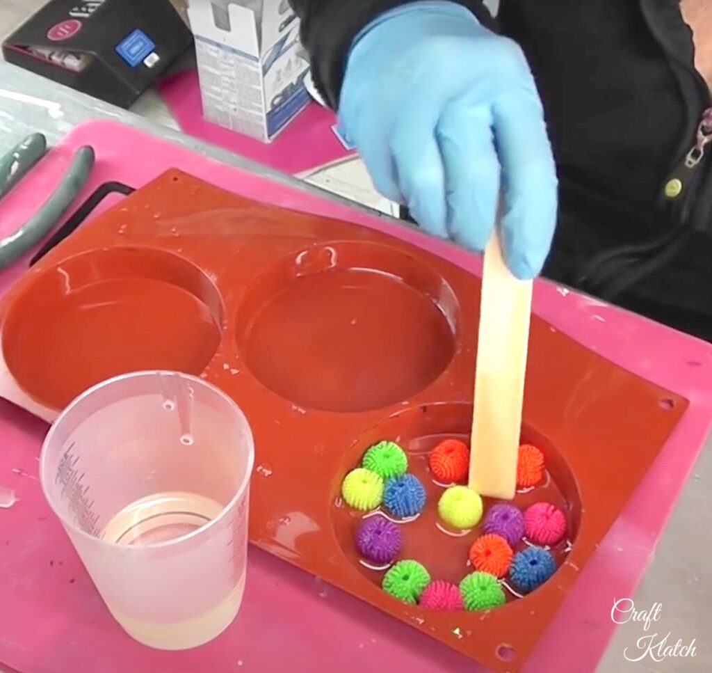 Move resin and koosh balls around coaster mold for even placement