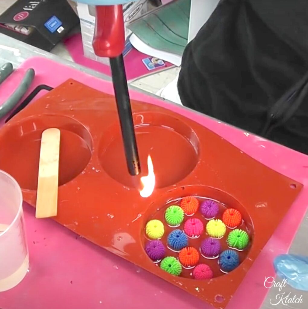 Use a lighter to pop the bubbles in the resin with the squishy balls