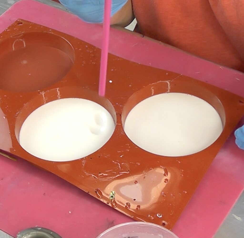 Using straw to pop bubbles in white resin