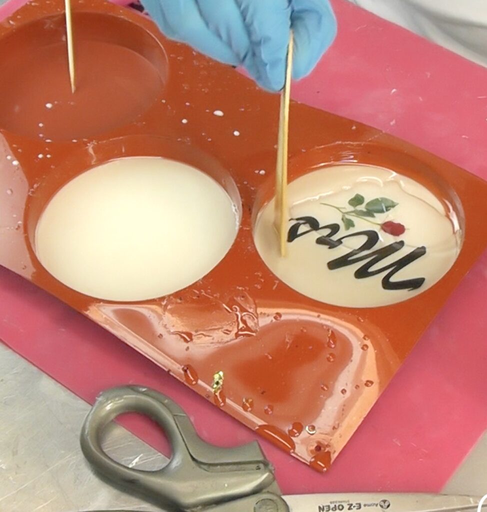 Use a stir stick to press down the transparency into the resin to remove bubbles