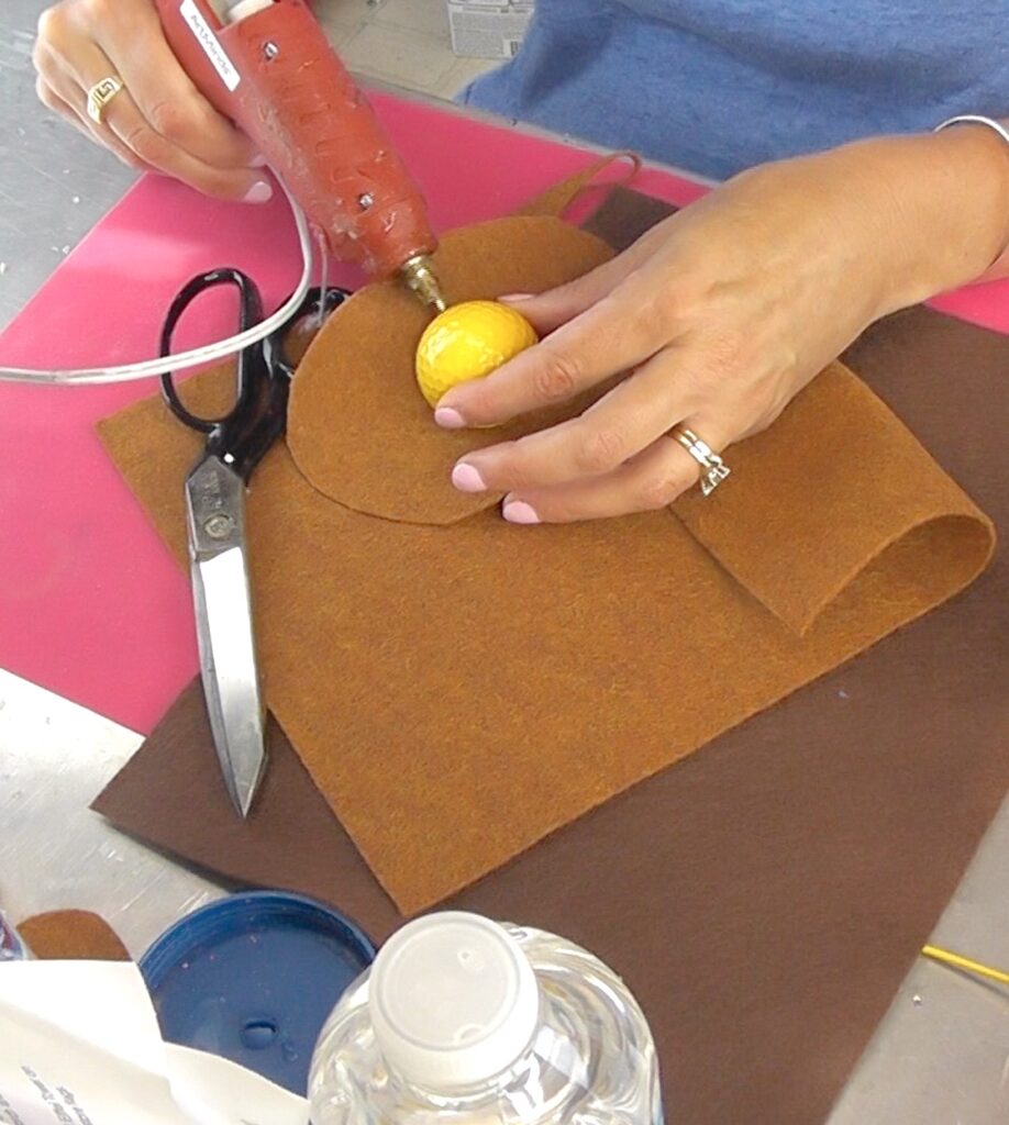 glue felt circle around yellow golf ball with hot glue