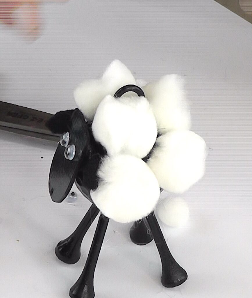 Glue white pom poms onto sheep's body