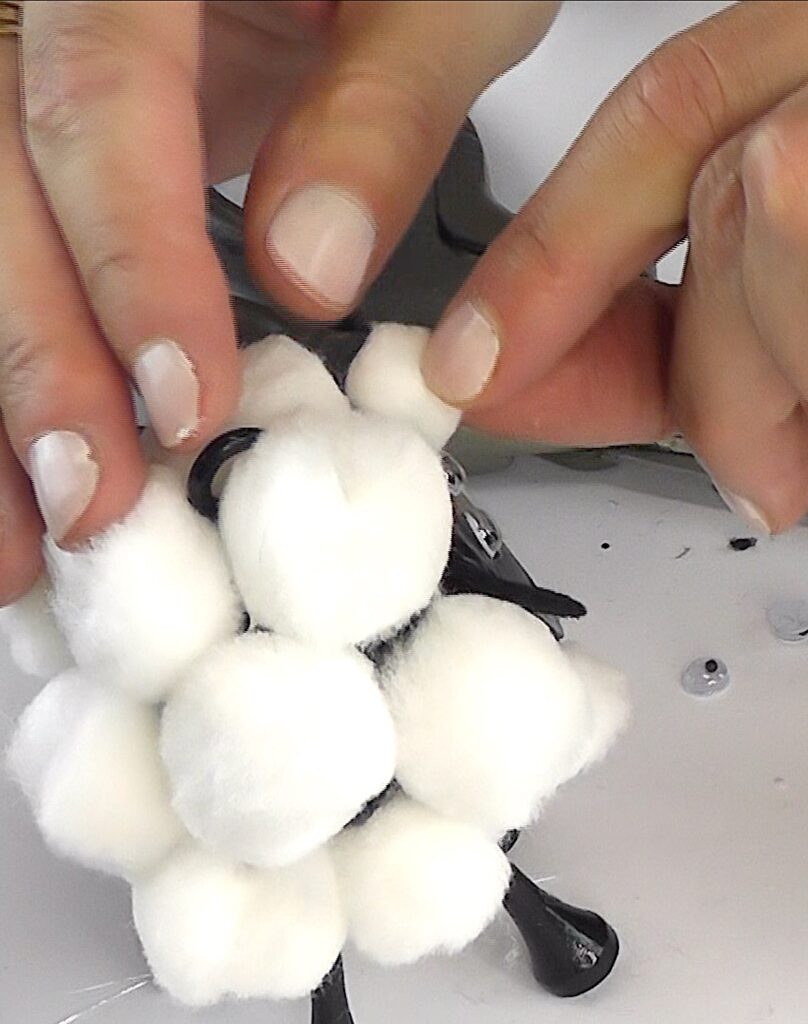 Glue white pom poms onto sheep's body