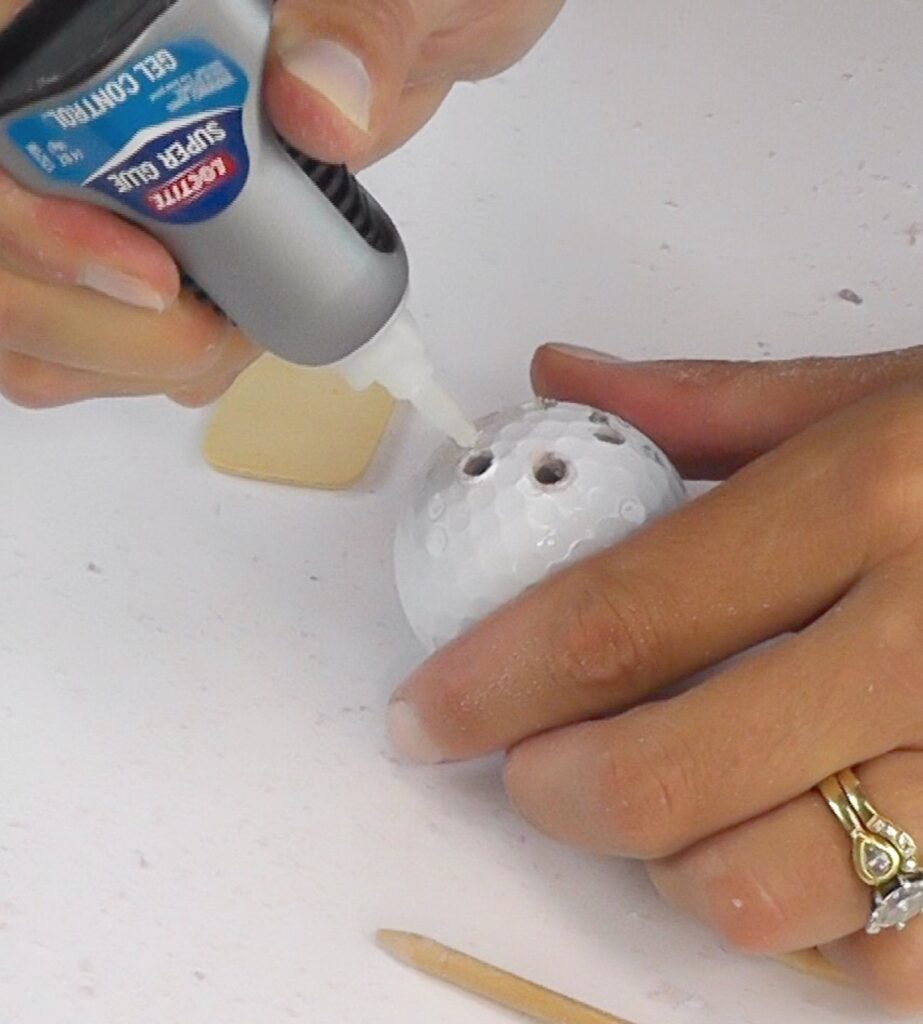 Put glue into the holes in the golf ball