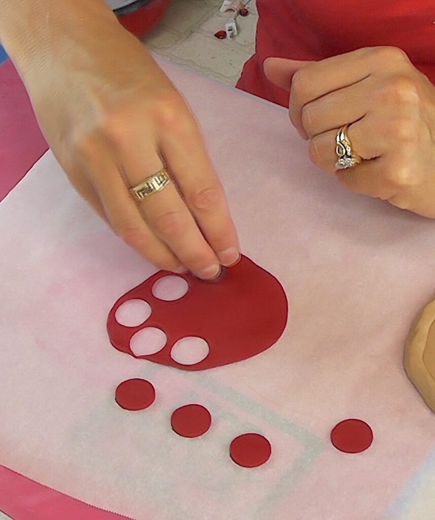 Roll red clay flat and use a small cookie cutter to cut out circles for pepperoni for the DIY pizza craft